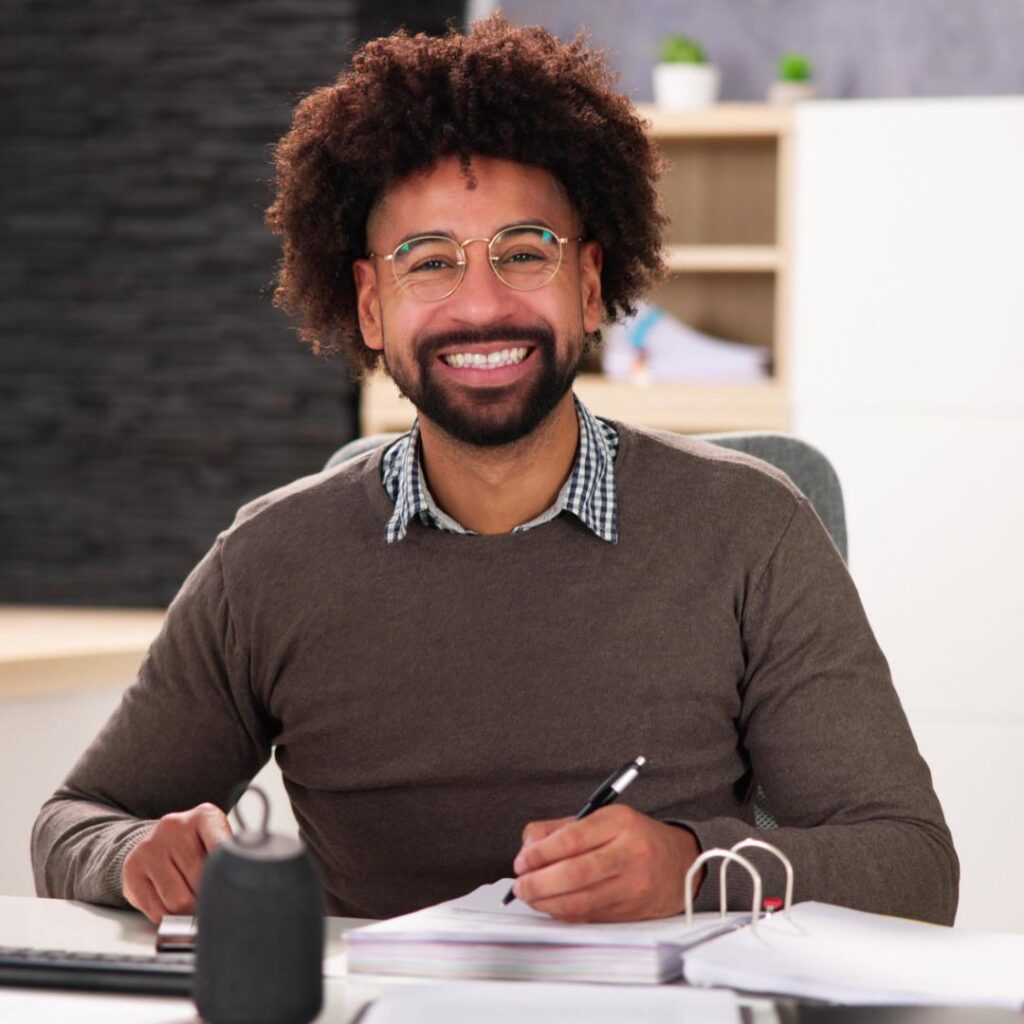 A professional speaker seated on a chair, preparing to address attendees at a business event.
